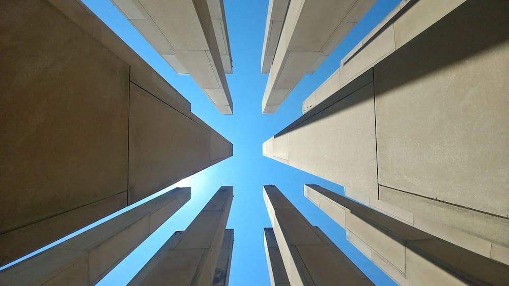 A view of tall, modern buildings converging towards the sky.