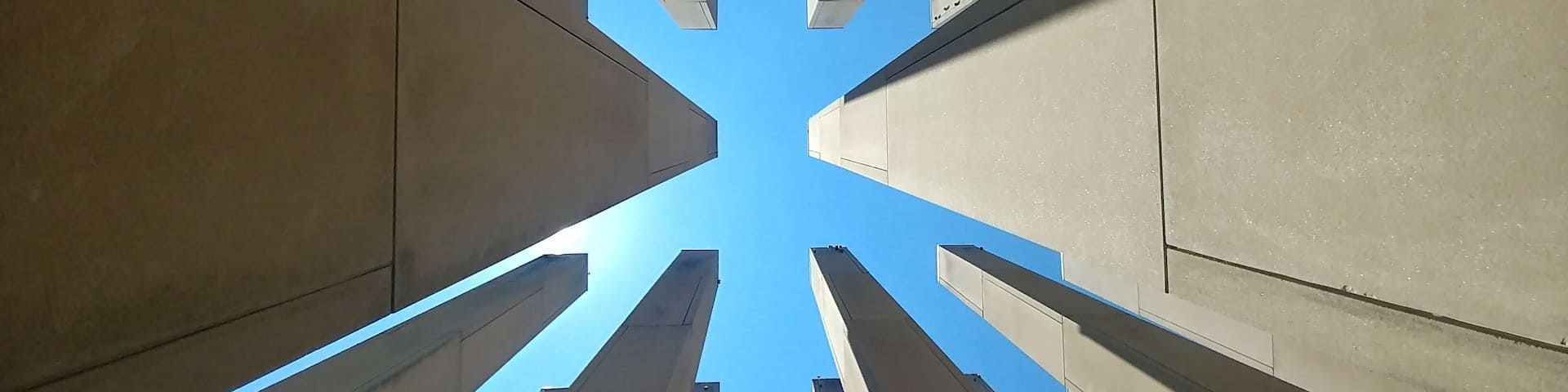 A view of tall, modern buildings converging towards the sky.