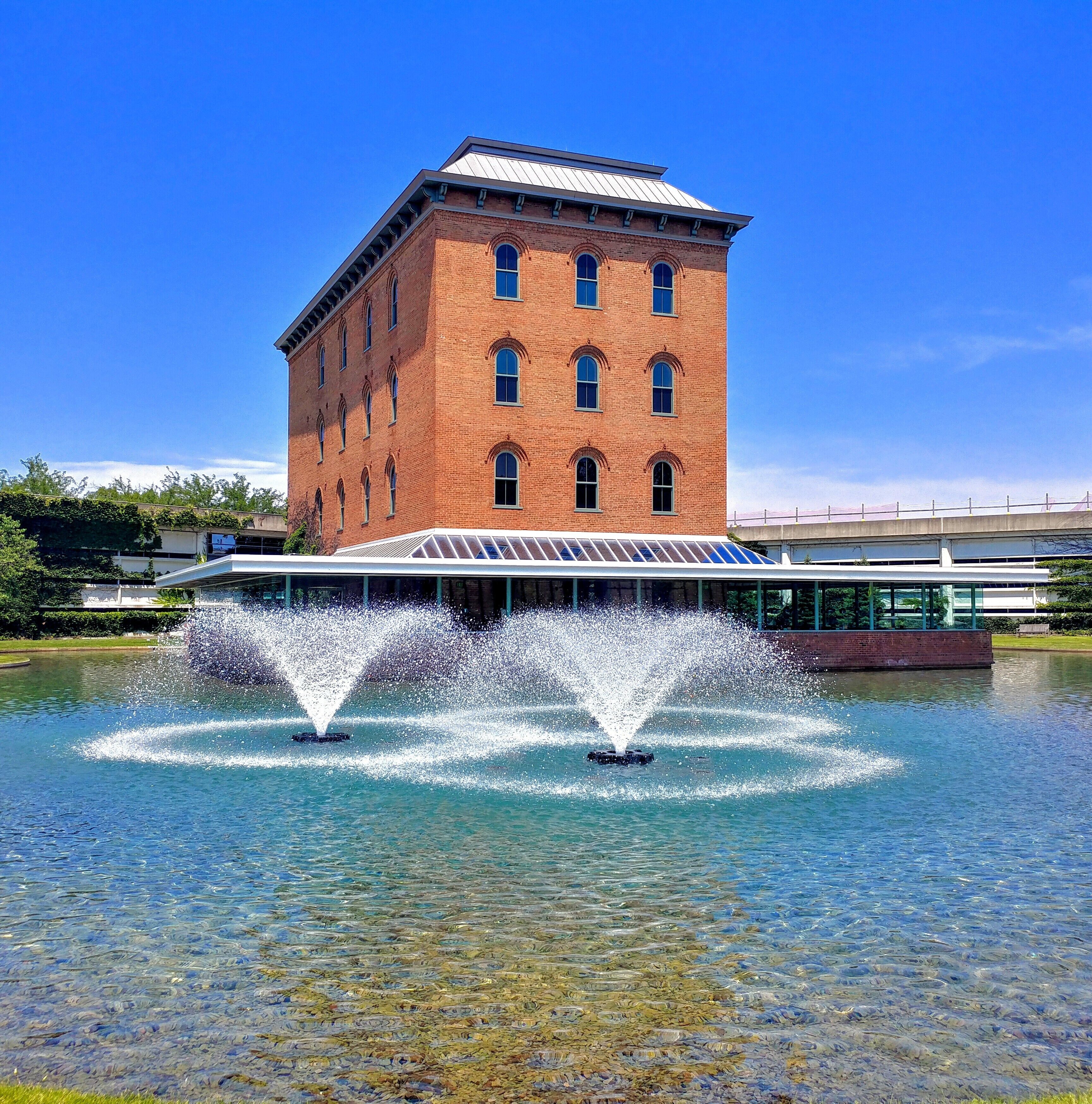 A brick building with a glass roof and a fountain in front.