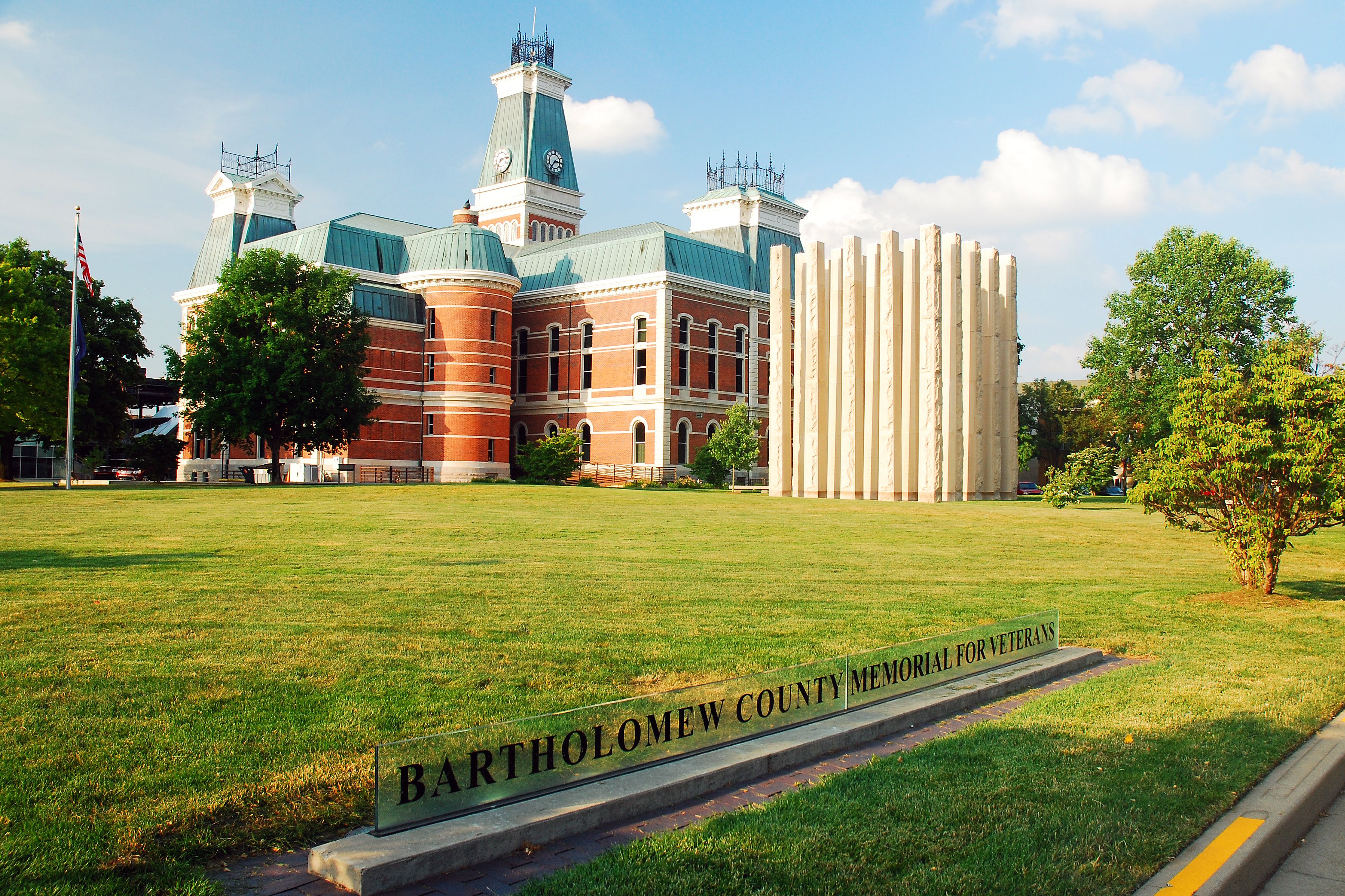 A historic building with a clock tower and a memorial sign for veterans.