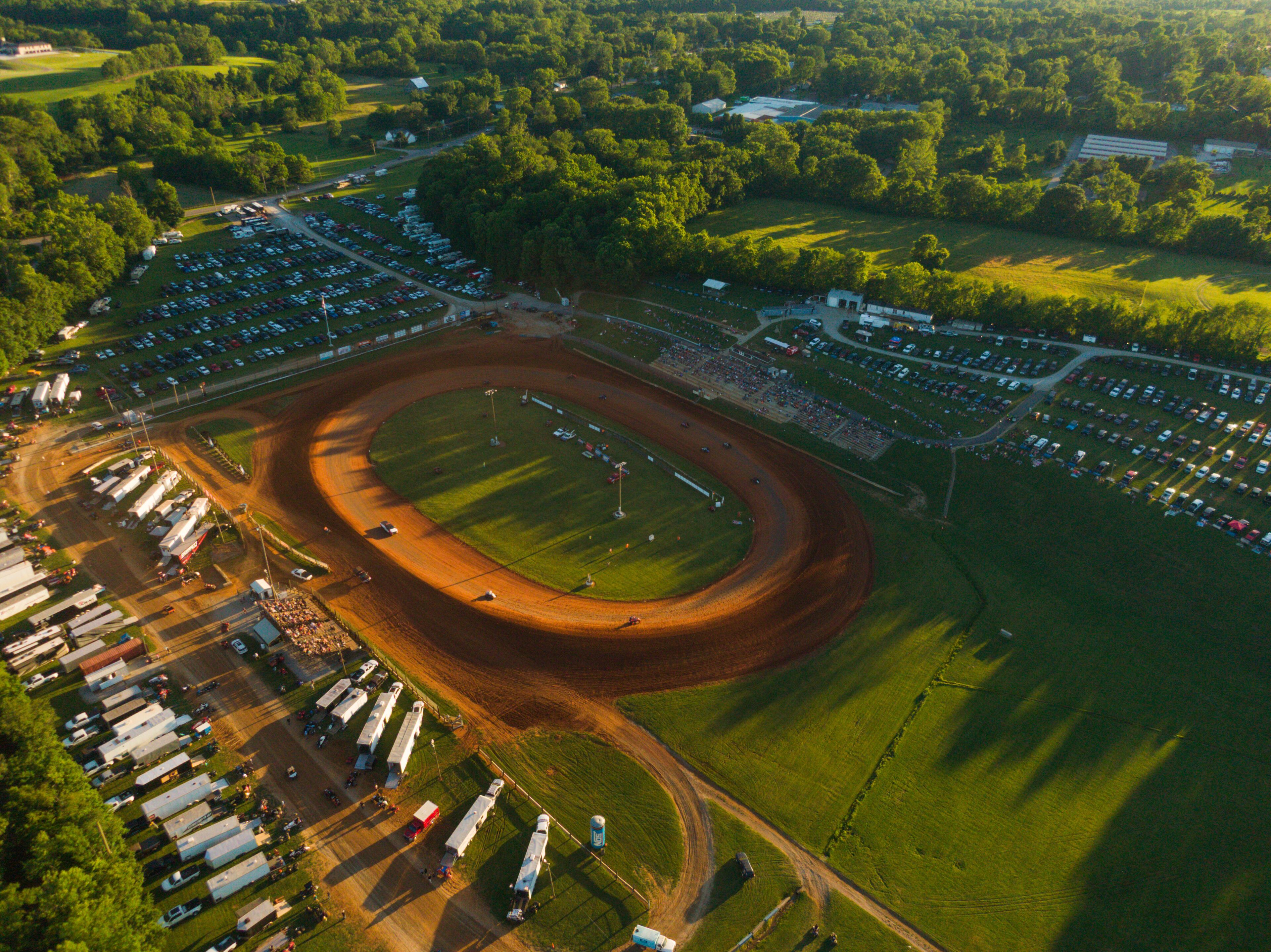 An aerial view of a racetrack surrounded by parking lots and green fields.