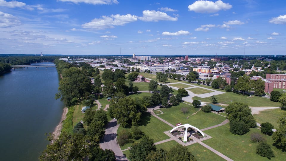 An aerial view of a city with a river, green parks, and a large white monument.