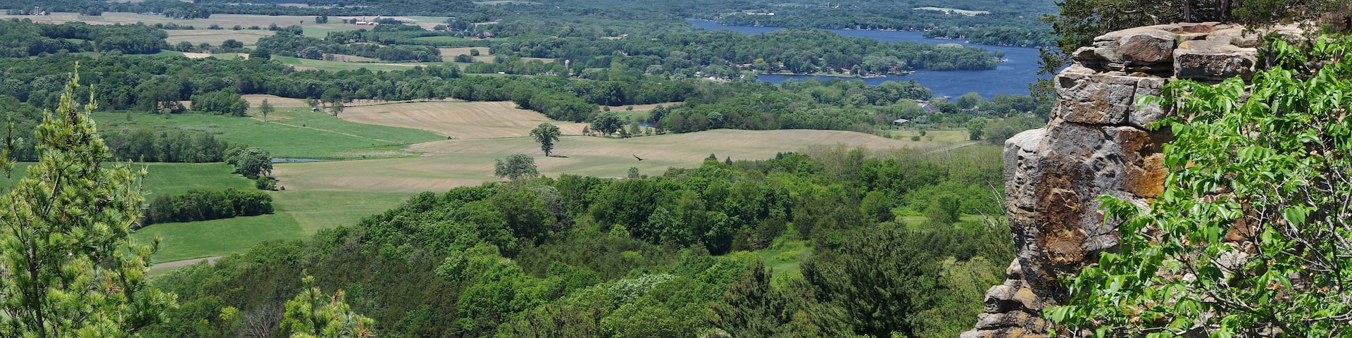 A mountainous landscape with a lake, dense forest, and a rocky outcrop.