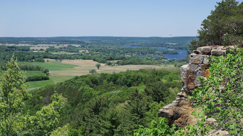 A mountainous landscape with a lake, dense forest, and a rocky outcrop.