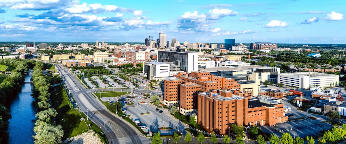 A cityscape with a river, modern buildings, and a clear blue sky.
