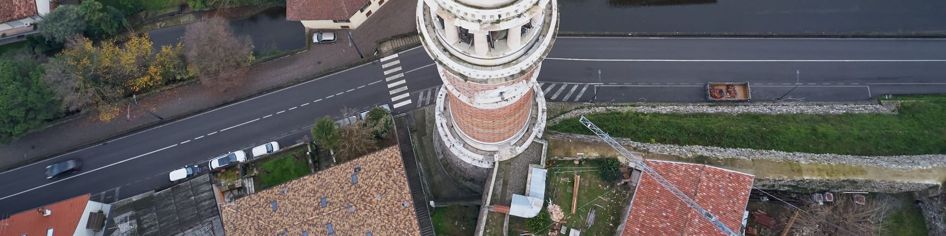 Panoramic aerial view of Torre Del Popolo a symbol of the city of Palazzolo sull'Oglio, Italy. Statue of San Fedele. Low clouds, mountains in the snow. Winter season. Aerial photography with drone