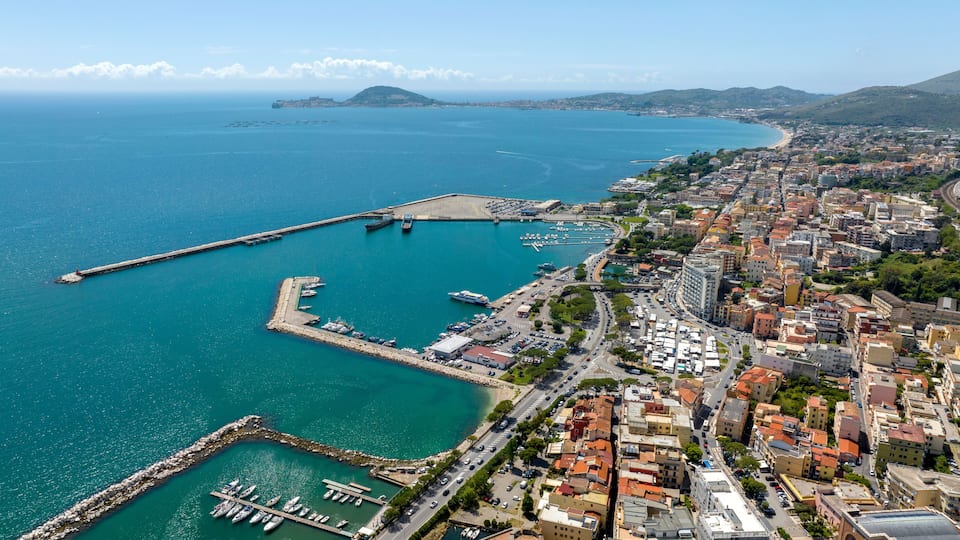 A coastal city with a marina, a long pier, and a densely built urban area.