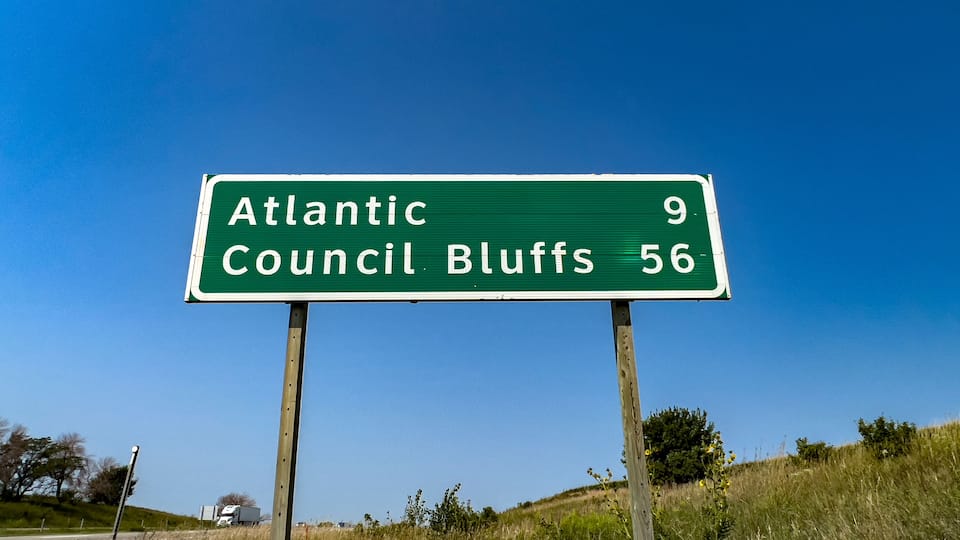 A green highway sign with white text indicating directions to Atlantic and Council Bluffs, with distances of 9 and 56 miles respectively.