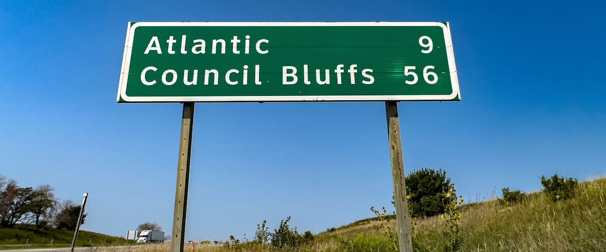 A green highway sign with white text indicating directions to Atlantic and Council Bluffs, with distances of 9 and 56 miles respectively.