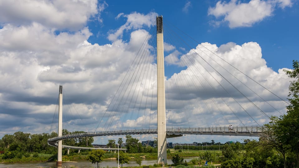 A cable-stayed bridge with two tall towers, a river below, and a clear sky with clouds.