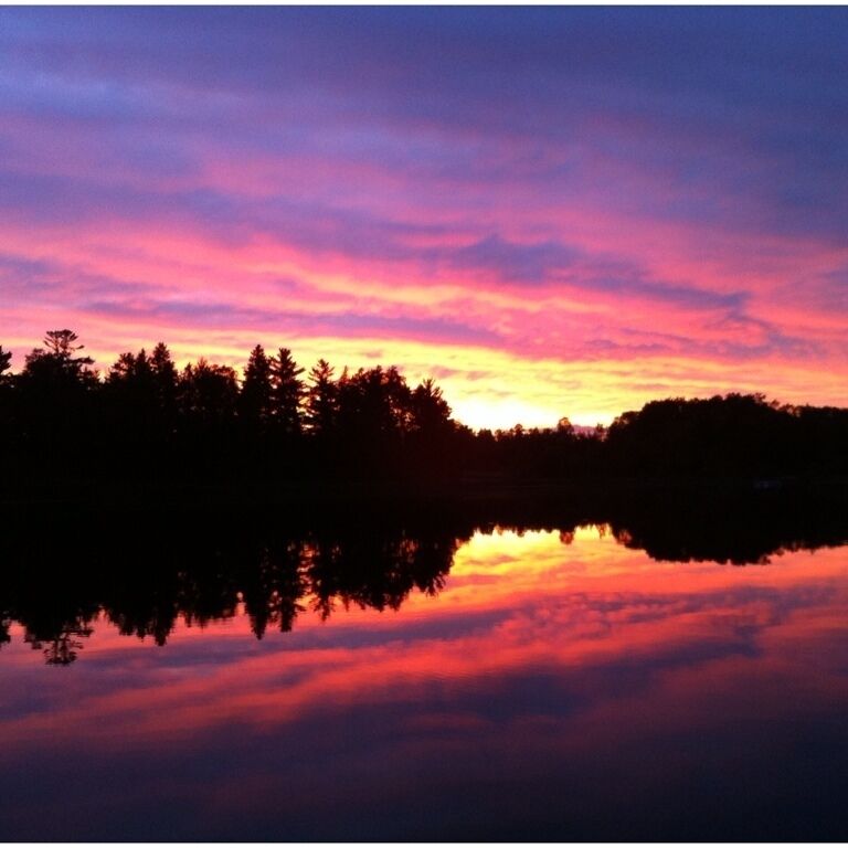 A sunset over a lake with a forest silhouette.