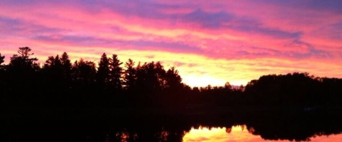 A sunset over a lake with a forest silhouette.