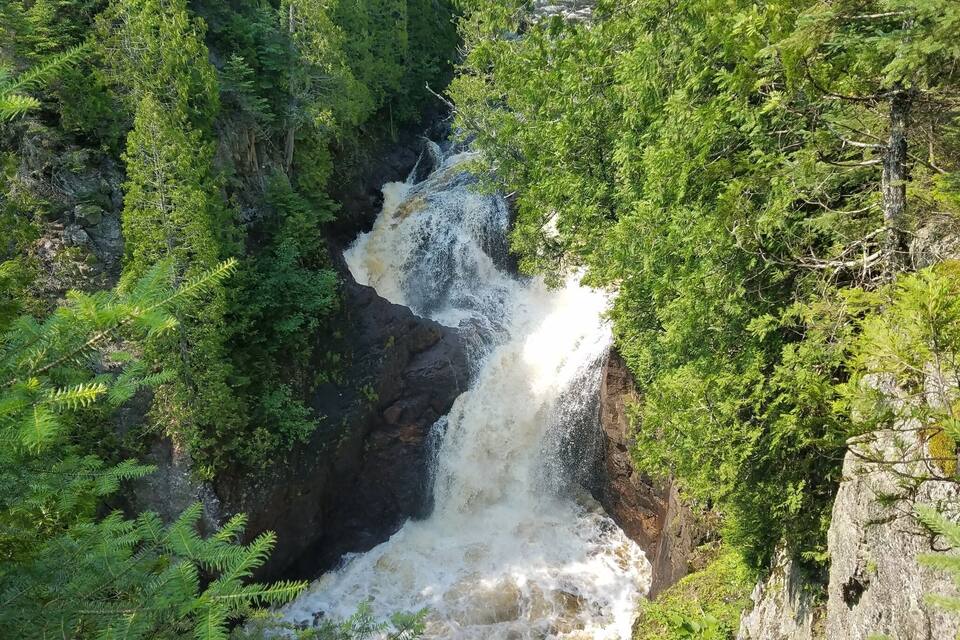 A waterfall cascading down a rocky cliff surrounded by dense green foliage.