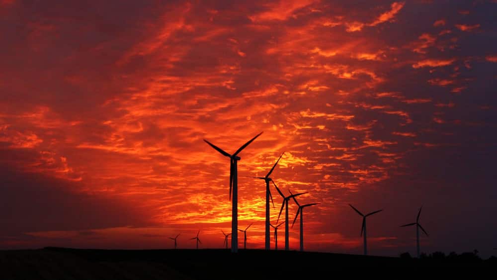 Wind turbines silhouetted against a vibrant sunset sky.