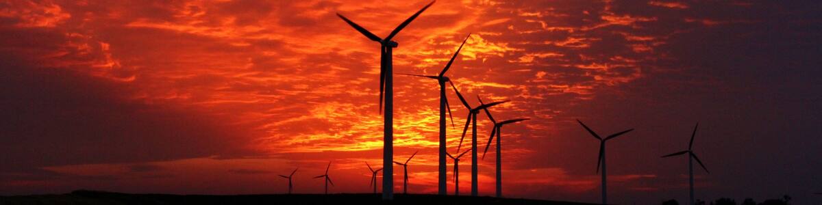 Wind turbines silhouetted against a vibrant sunset sky.
