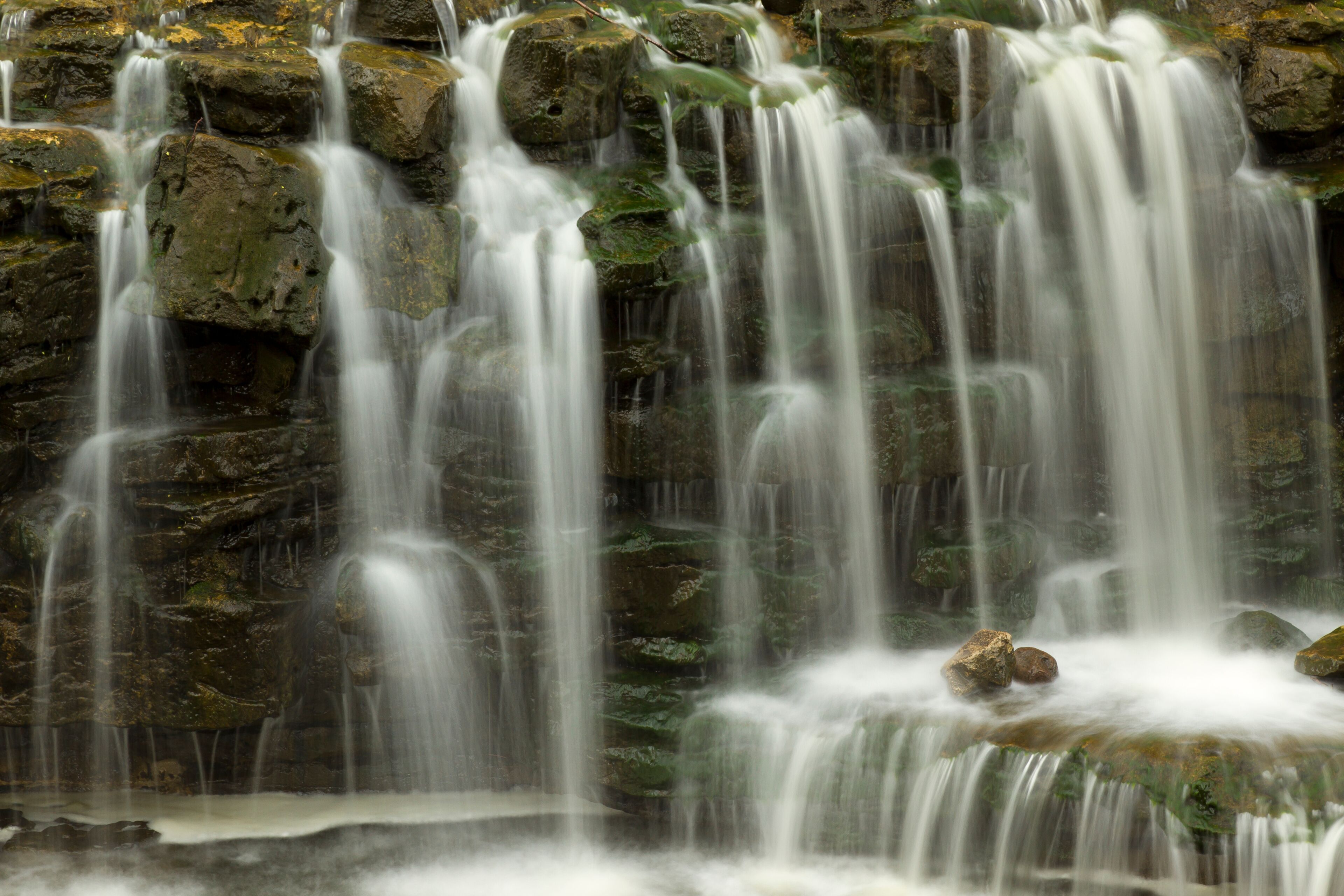 A waterfall cascading over rocks with moss-covered surfaces.