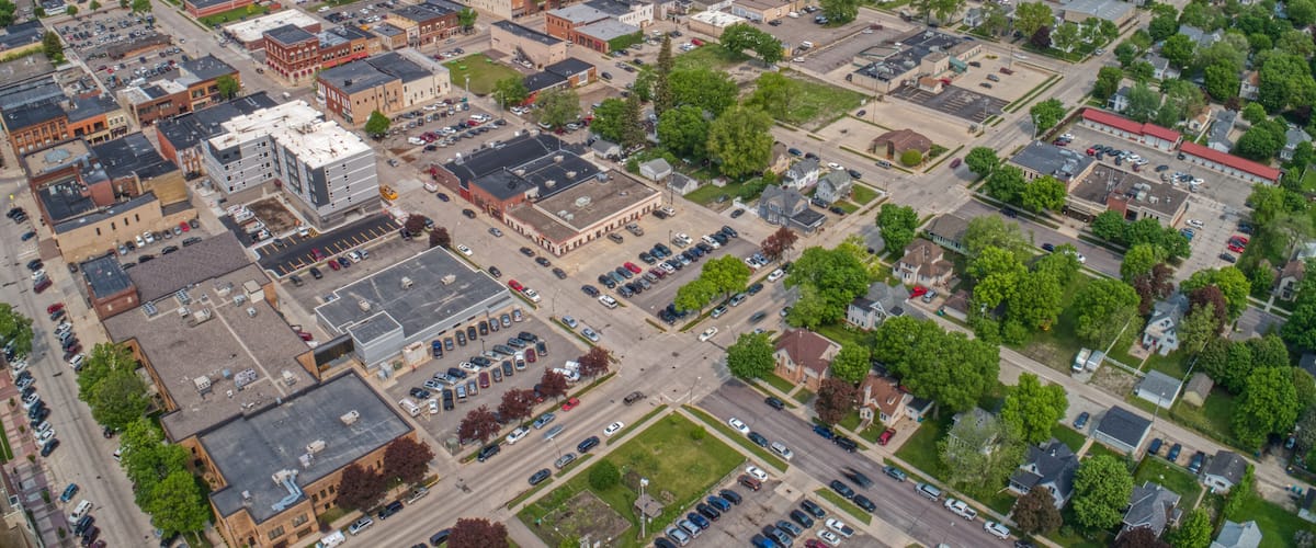 An aerial view of a city with a mix of commercial and residential buildings, roads, and green spaces.