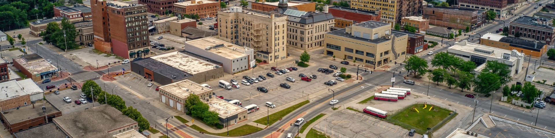 An aerial view of a city with a central roundabout, surrounding buildings, and a distant church steeple.
