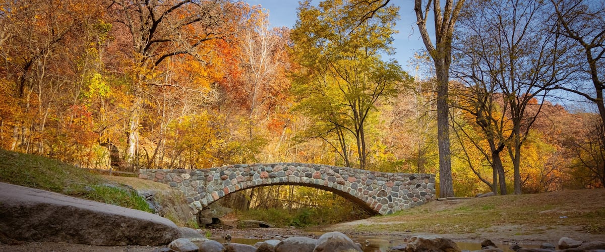 Pedestrian rock bridge over Peas Creek in Ledges State Park, Iowa, during fall