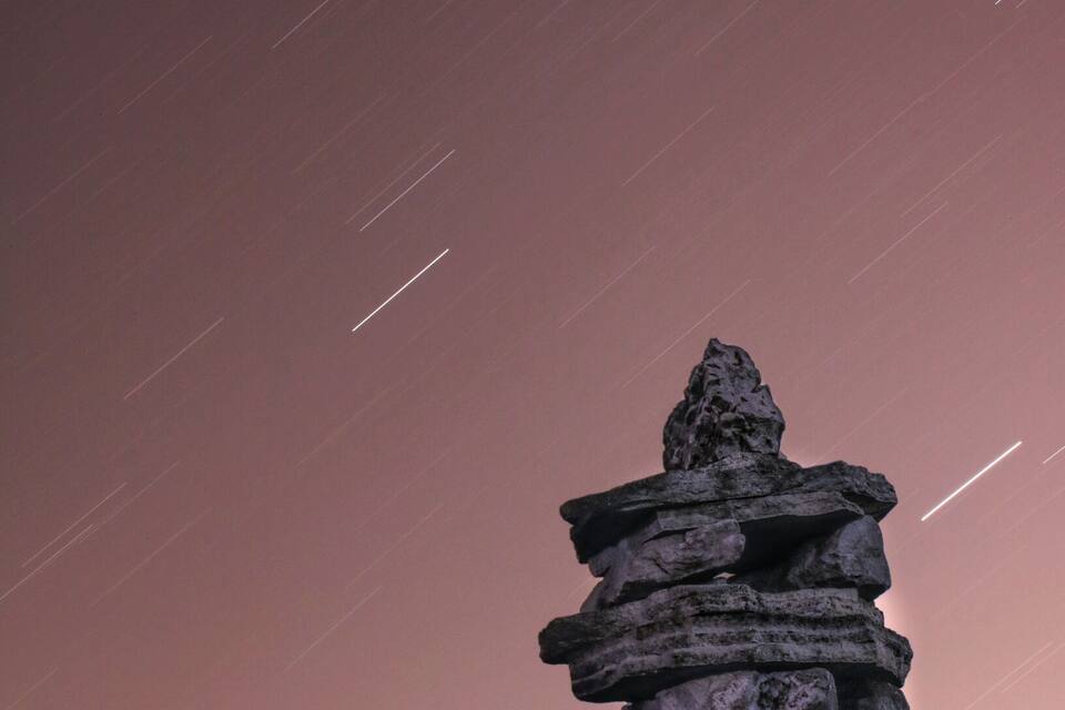 Eine Steinkonstruktion vor einem Zwielichtenhimmel mit deutlich sichtbaren Sternspuren.