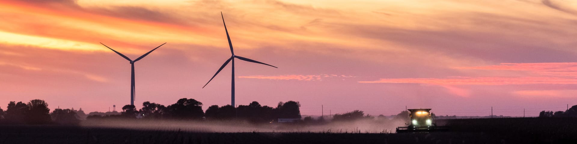 tractor harvesting a field at sunset on a Iowa farm