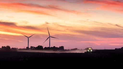 tractor harvesting a field at sunset on a Iowa farm
