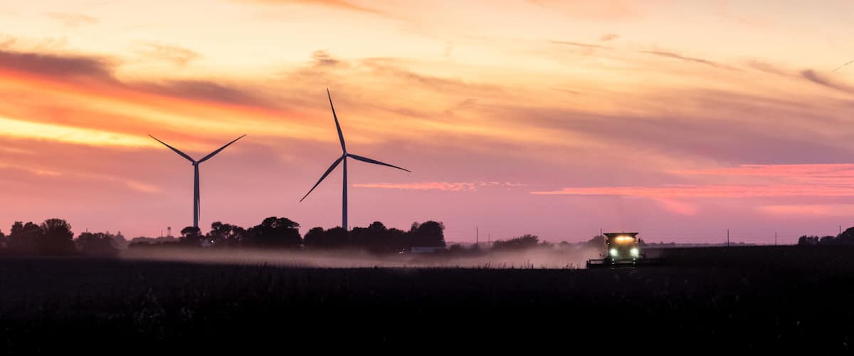 tractor harvesting a field at sunset on a Iowa farm