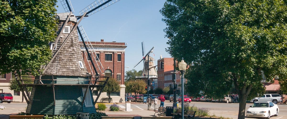 A windmill, benches, and a street with cars and pedestrians.