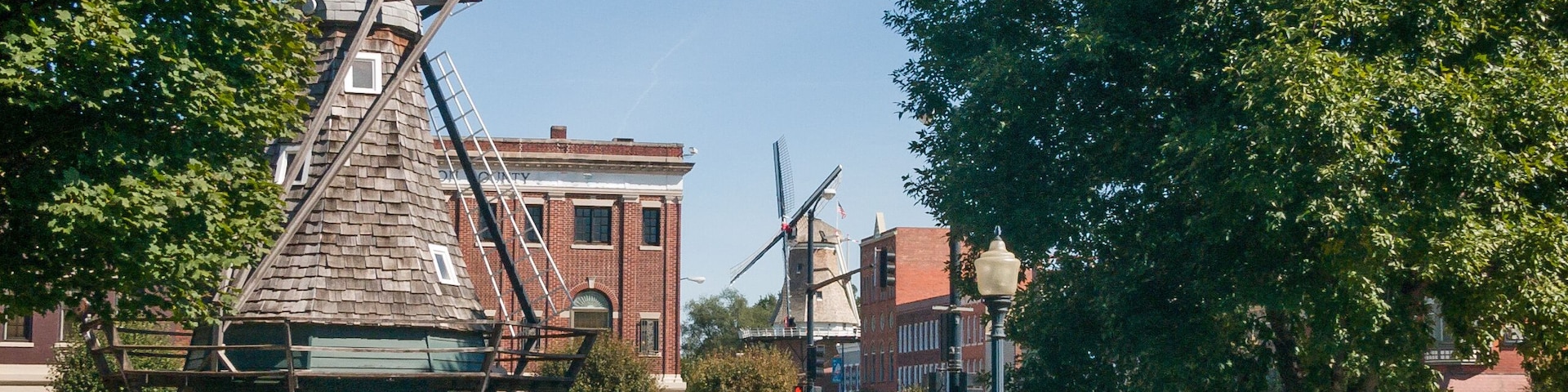 A windmill, benches, and a street with cars and pedestrians.