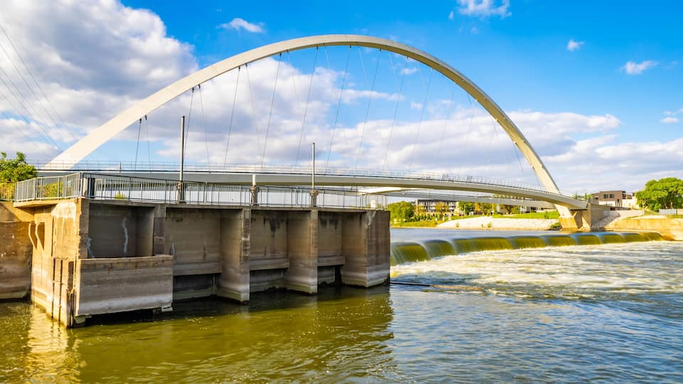 A large arched bridge over a river with a clear sky.