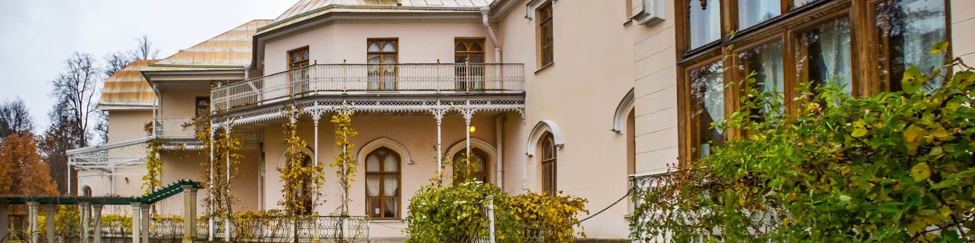 A historic building with a balcony, a fountain, and a garden.