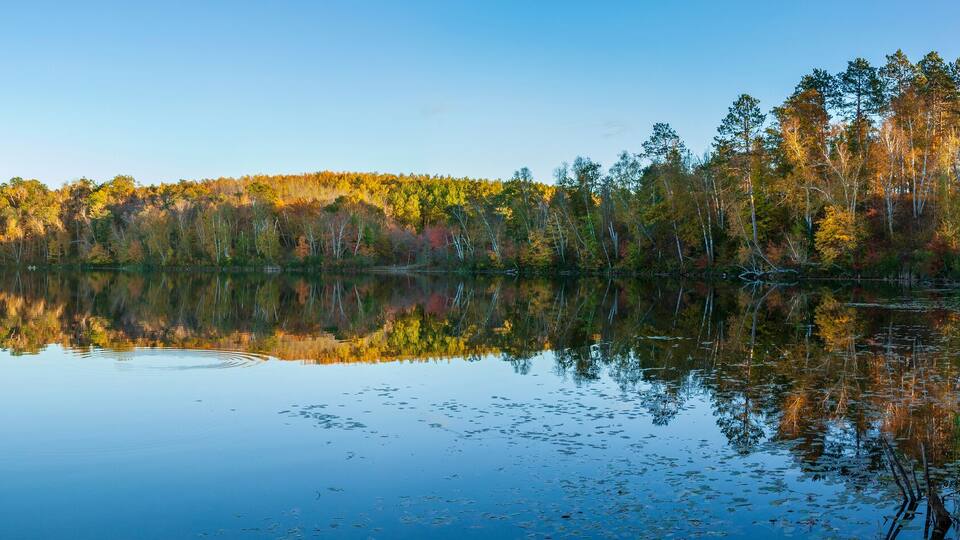 A calm lake surrounded by autumn-colored trees.