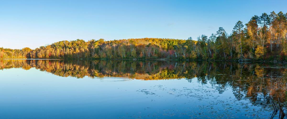 A calm lake surrounded by autumn-colored trees.