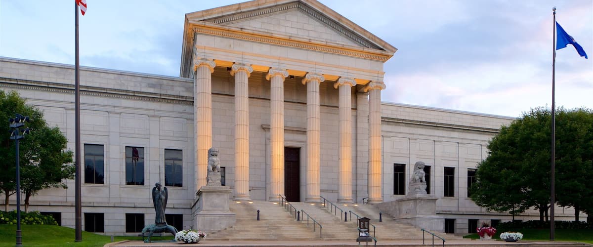 A neoclassical building with a portico, steps, and statues.