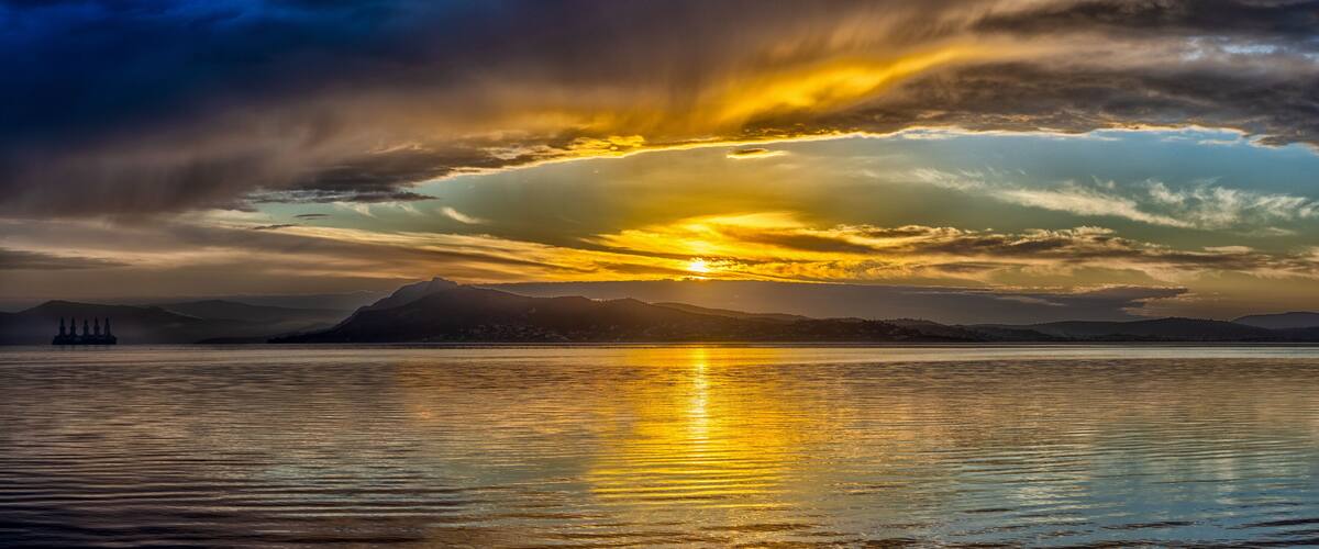 A sunset over a calm lake with mountains in the background.