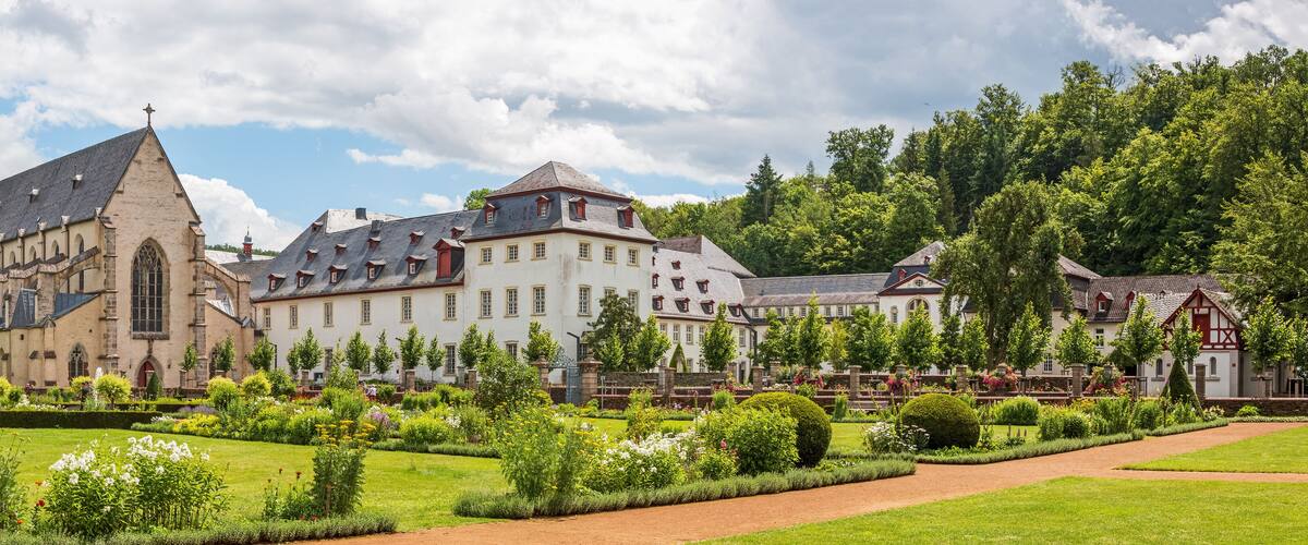 A historic church with a tall spire, surrounded by well-manicured gardens and traditional European architecture.