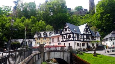 A traditional half-timbered building, a stone bridge, and a castle in the background.