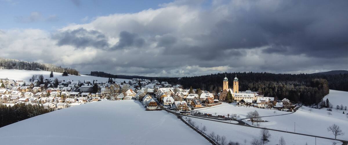 A snow-covered village with houses, a church, and a tower.