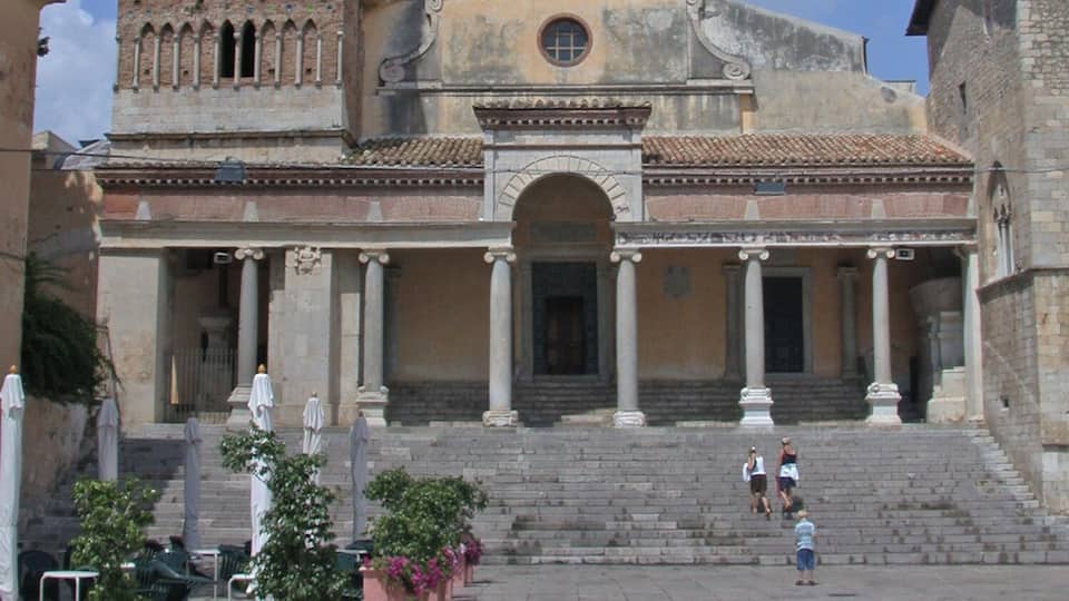 A historic church with a bell tower and a courtyard with potted plants.
