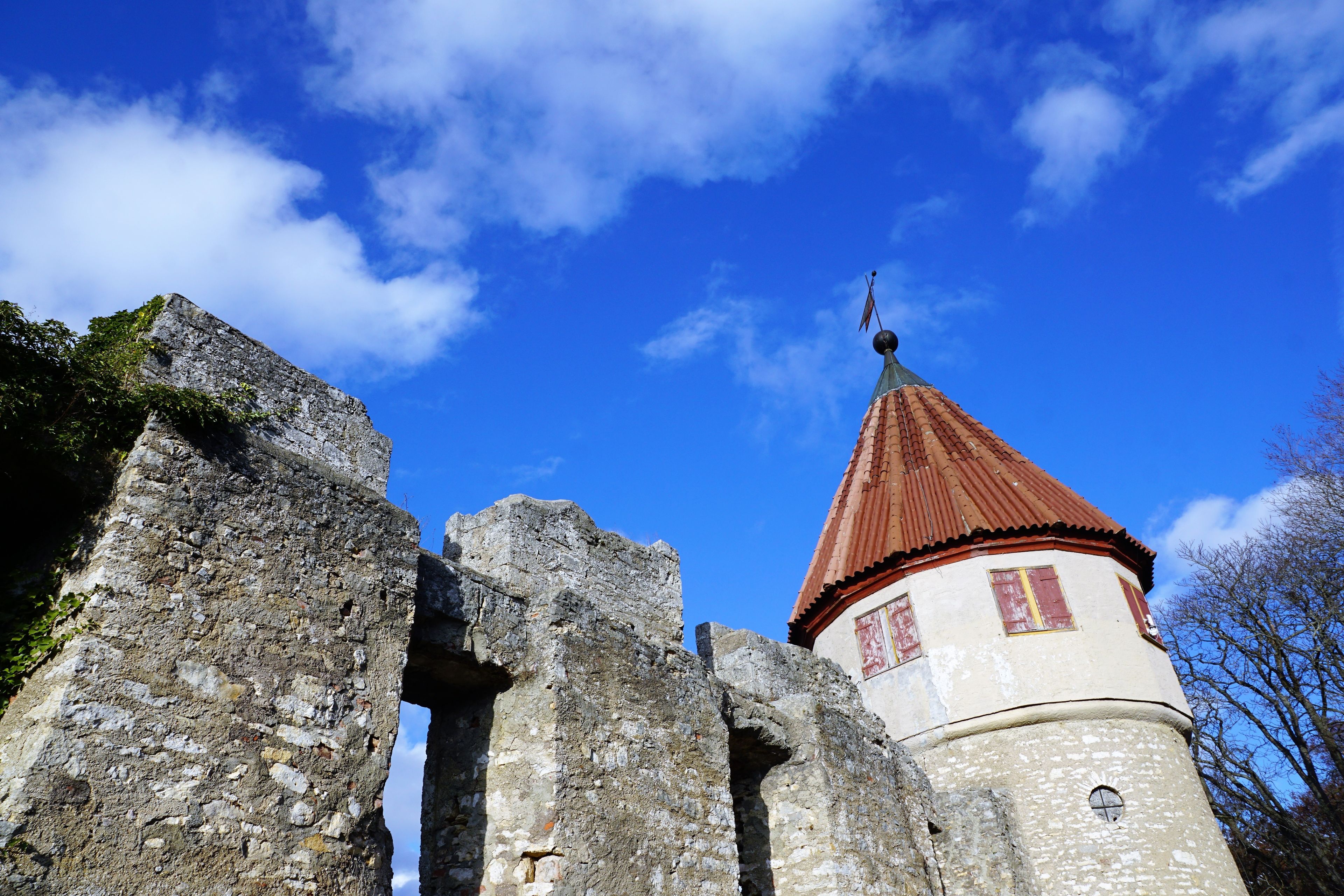 A stone tower with a red roof and a weather vane.