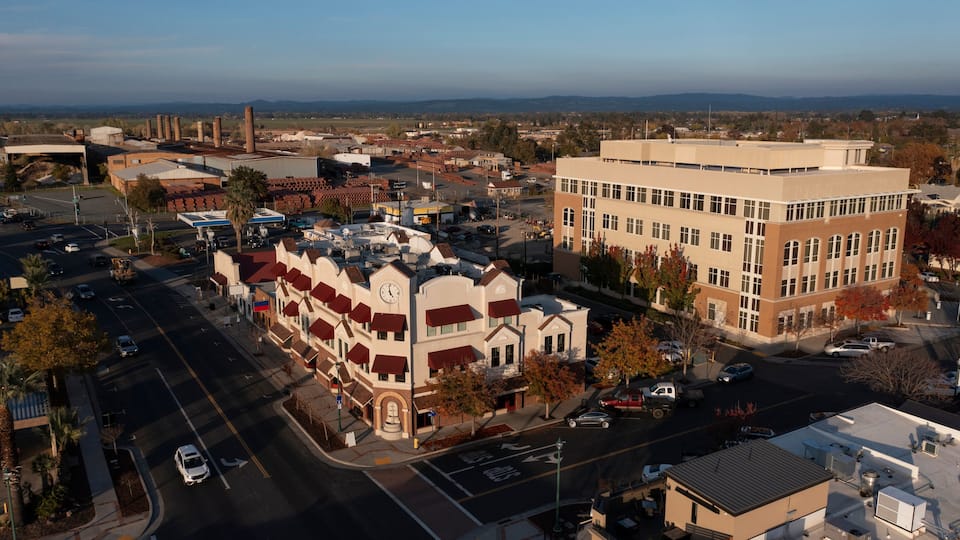 An aerial view of a town with a prominent clock tower, a large industrial complex, and a mix of residential and commercial buildings.
