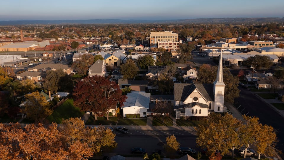 A town with a prominent church steeple, residential houses, and a large building in the center.