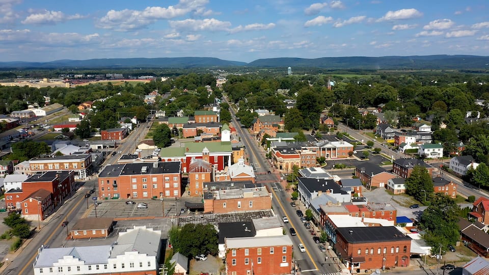 A town with historic buildings, a church steeple, and a distant mountain range.