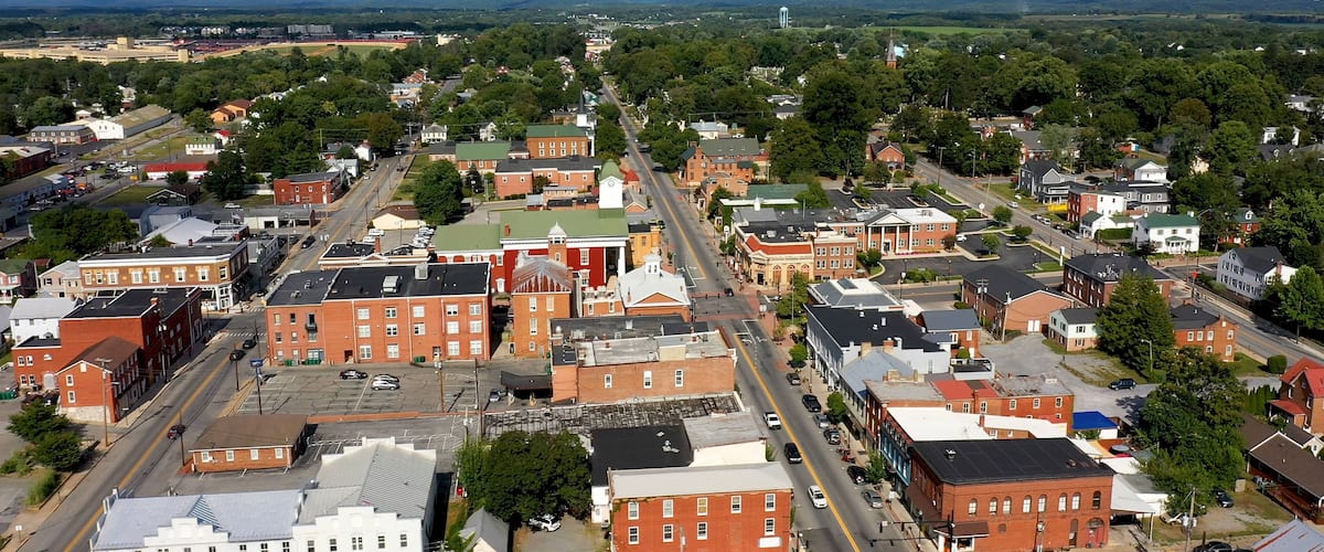 A town with historic buildings, a church steeple, and a distant mountain range.