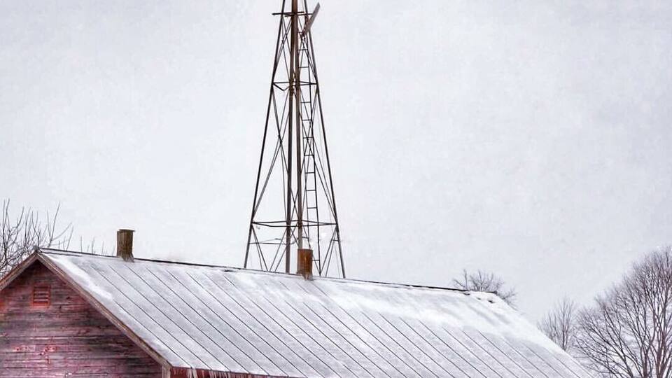 A windmill with a red barn in the foreground.