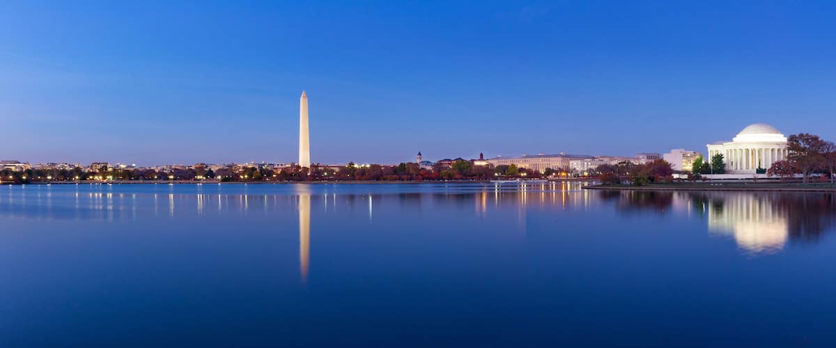 The Washington Monument, the Lincoln Memorial, and the National Mall with a calm lake reflecting the buildings.
