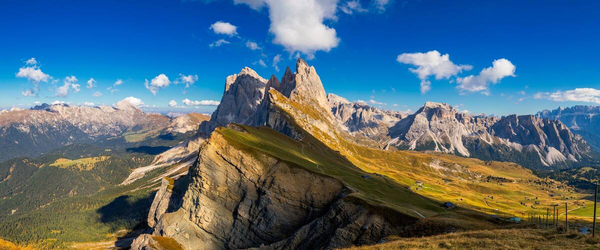 A mountain peak with a steep, rocky face and a grassy slope.