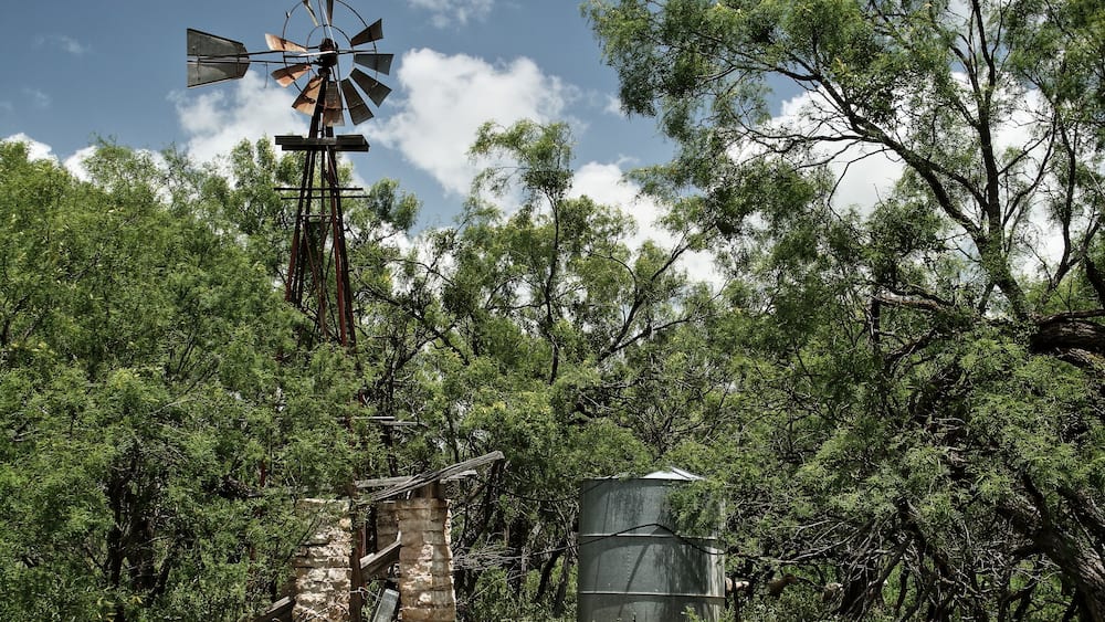 A windmill, a water tank, and a stone structure in a forest.