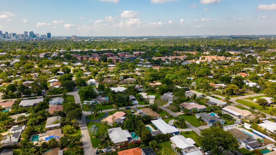 An aerial view of a residential area with houses, roads, and greenery.