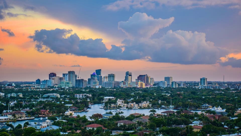 A city skyline with a river and surrounding greenery.